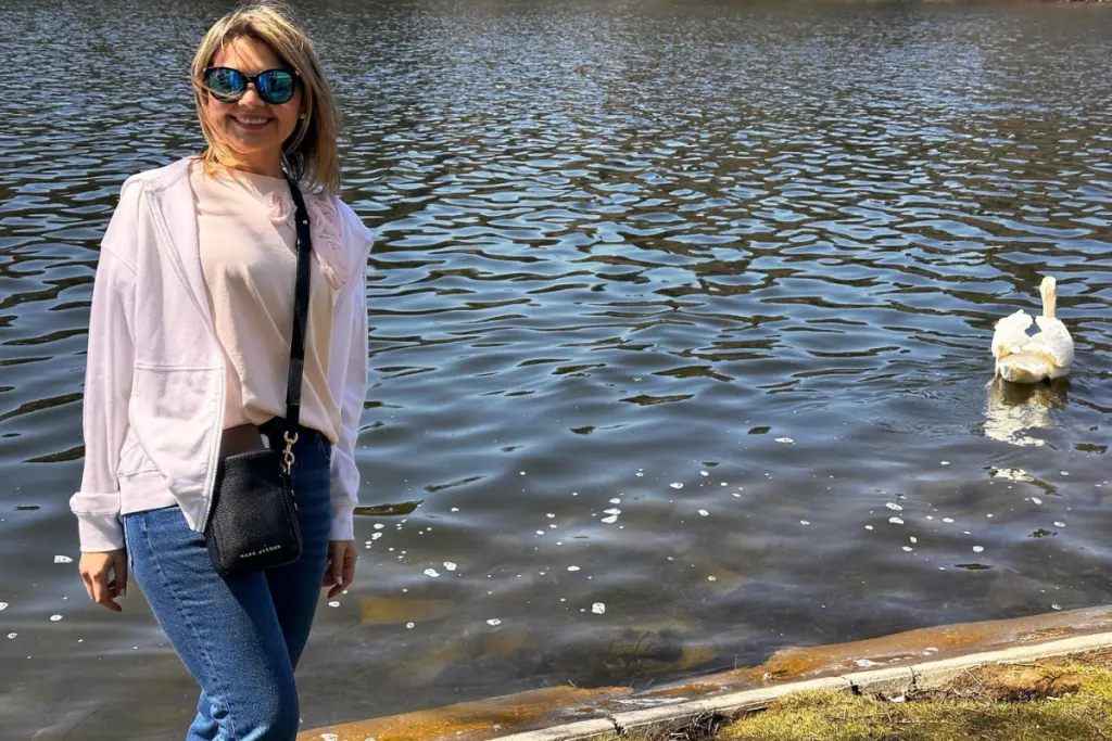 Ola Joha enjoying a peaceful day by the lake with a swan nearby.