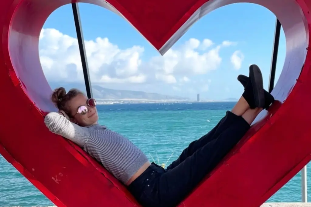 Sierra Day relaxing by the ocean while posing inside a heart-shaped sculpture during her travels.