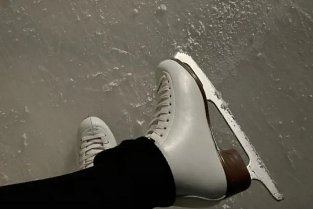 Figure skates on an ice rink, highlighting Stephanie Pettinaro’s long-time passion for figure skating.