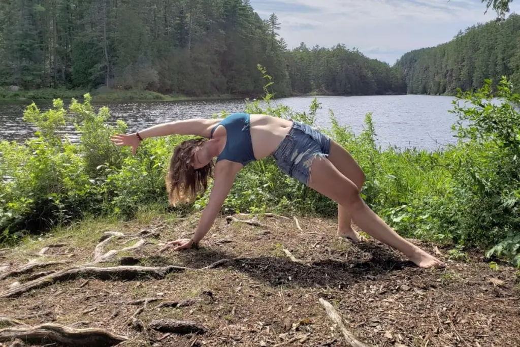 Taylor Bonin practicing yoga beside a peaceful lakeside surrounded by nature.