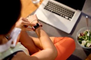 Person using a wearable fitness tracker to monitor health metrics and support personalized wellness goals