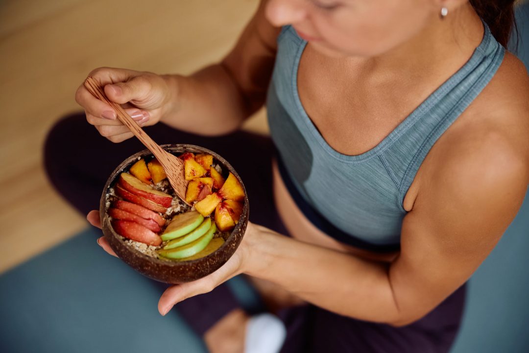 Close up of athlete eating healthy food after her sports training.